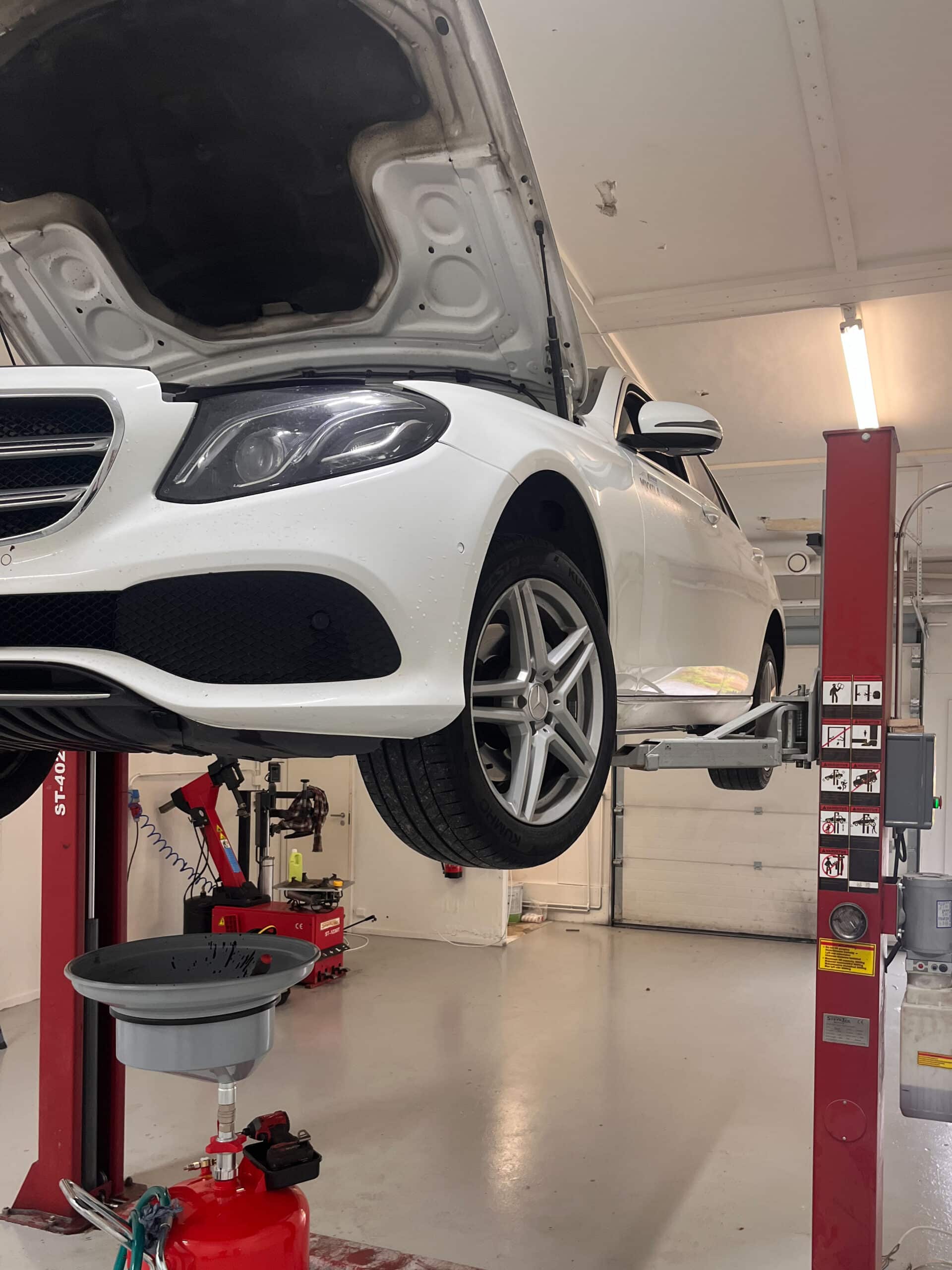 Henkilöauto nosturilla Mikkolan autohuollossa